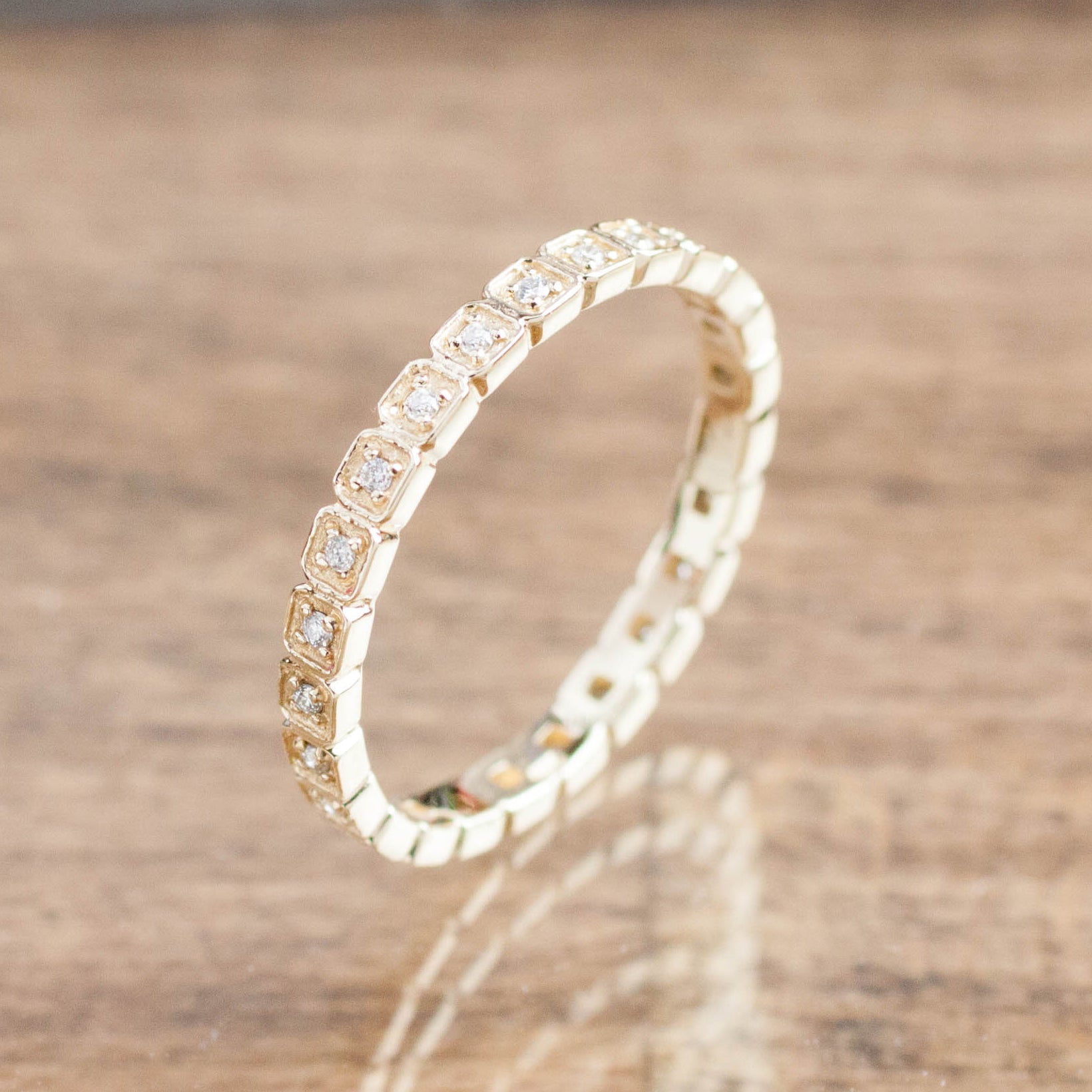 Hazel Eternity Ring with natural white diamonds set in ethically sourced solid gold on wooden surface background