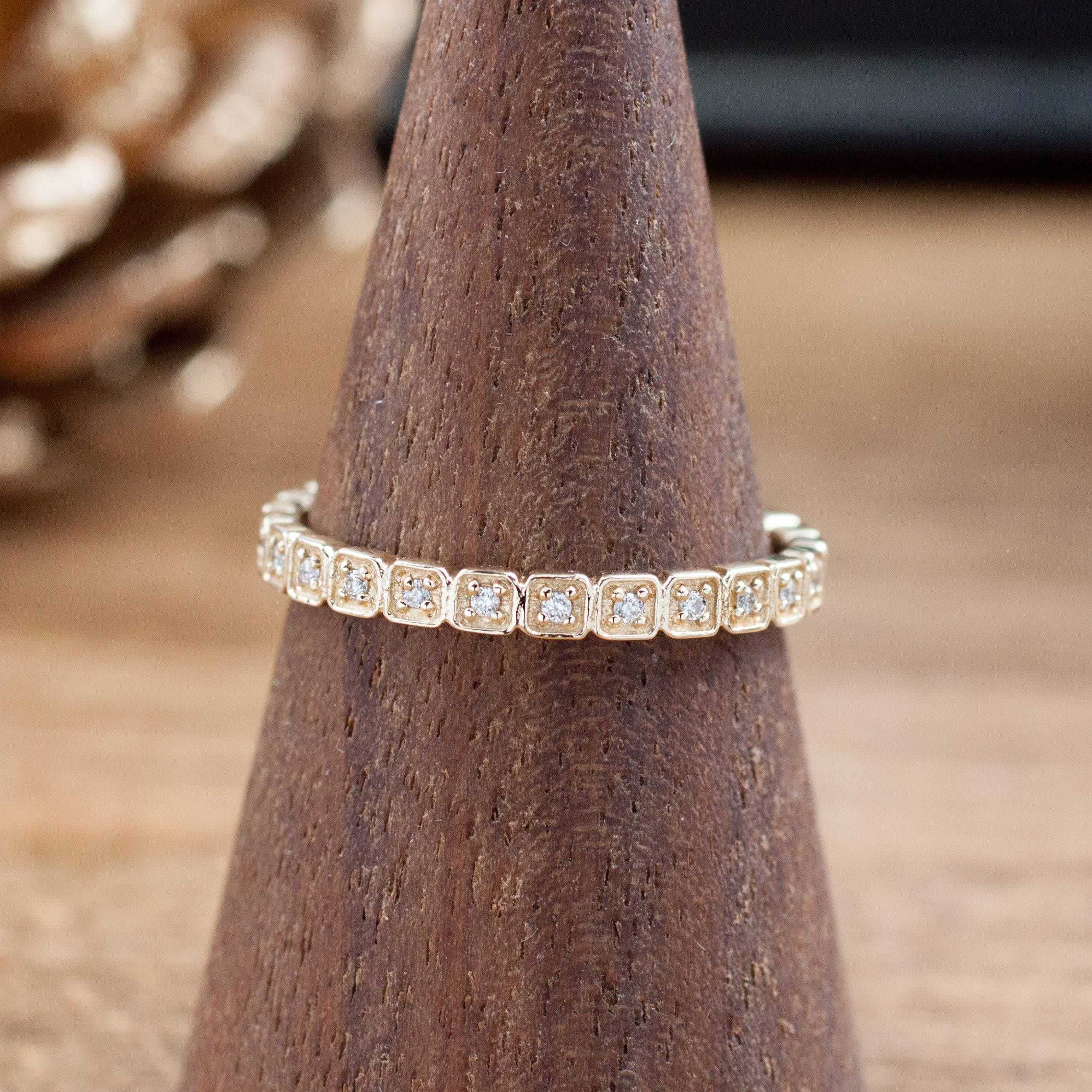 Hazel Eternity Ring with natural white diamonds set in solid gold on a wooden ring display cone