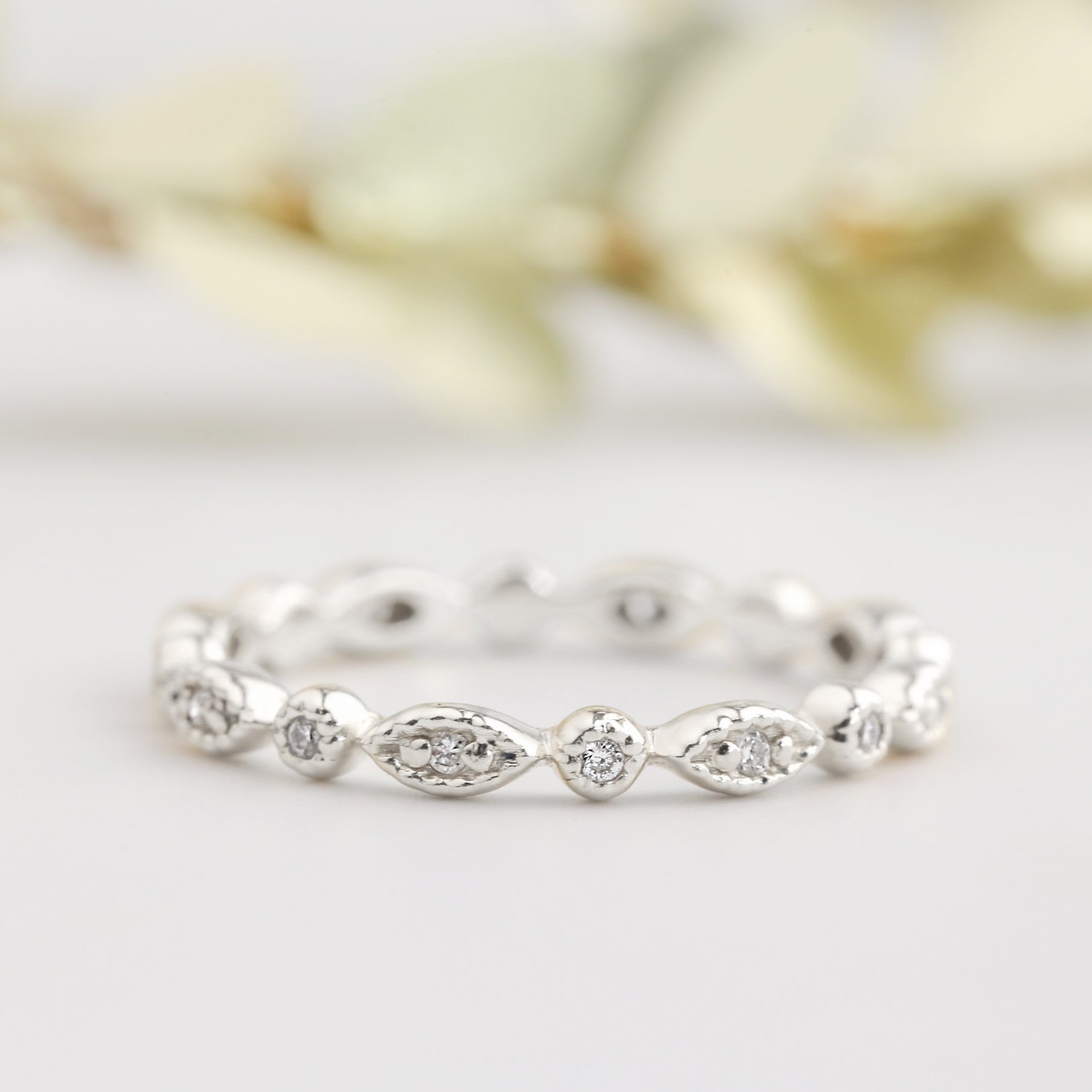 Close-up of an art-deco inspired petite eternity ring with natural white diamonds and milgrain detailing in solid gold