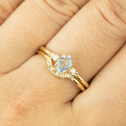 Close-up of Isabel's Curved Ring in solid gold with natural white diamonds on a hand against a light background