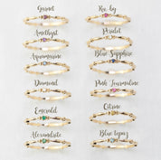 Twelve 14k gold birthstone rings including ruby, sapphire, emerald, diamond, garnet, amethyst, and others in size 7 displayed on white background.