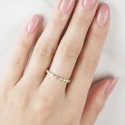 Close-up of a hand wearing a Seren Ring with natural white diamonds in a delicate solid gold band.