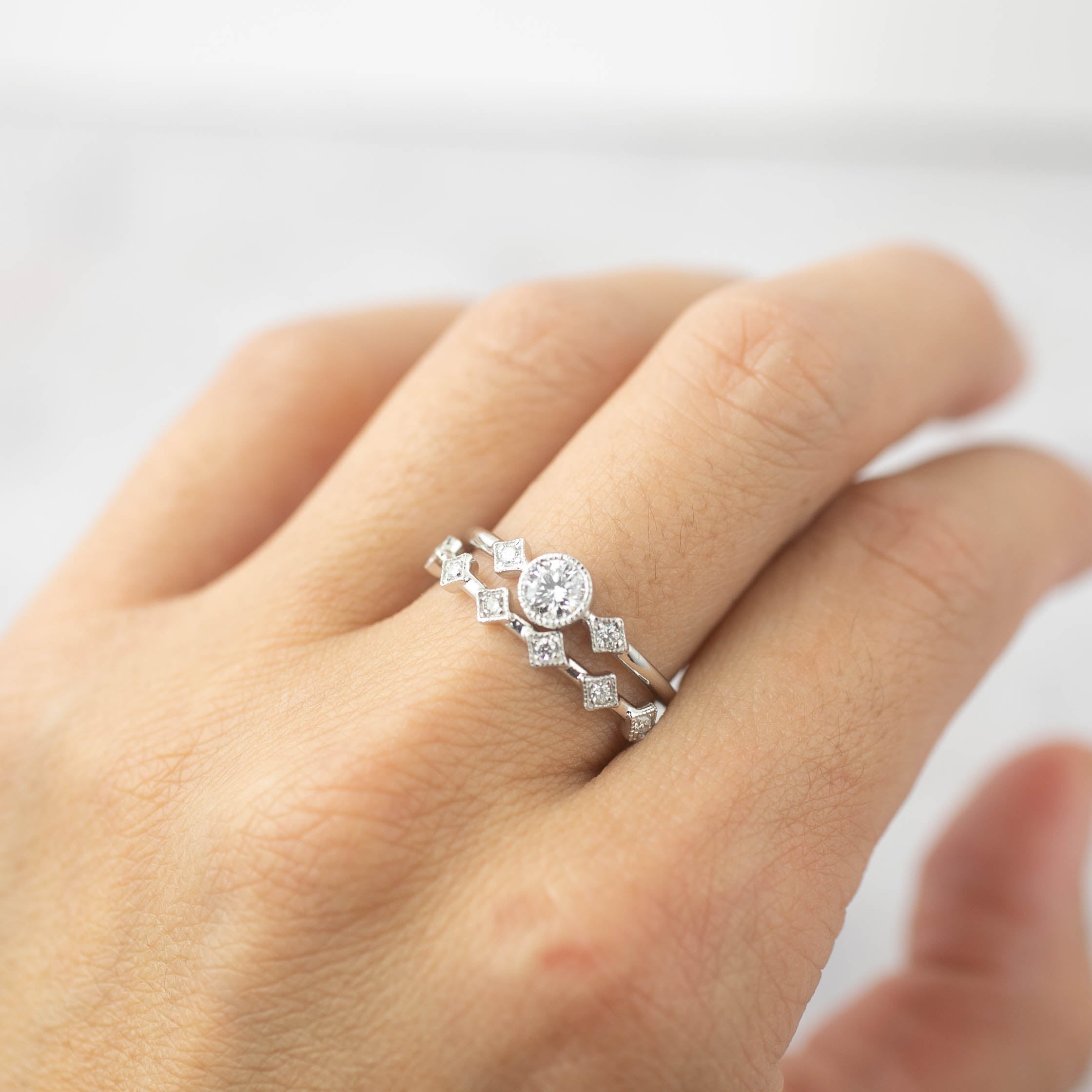 Hand wearing Moon & Star ring set with brilliant-cut diamonds and milgrain bezel setting on white gold band