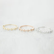 Three Six Star Rings in gold, rose gold, and silver with natural white diamonds on a soft gray background.