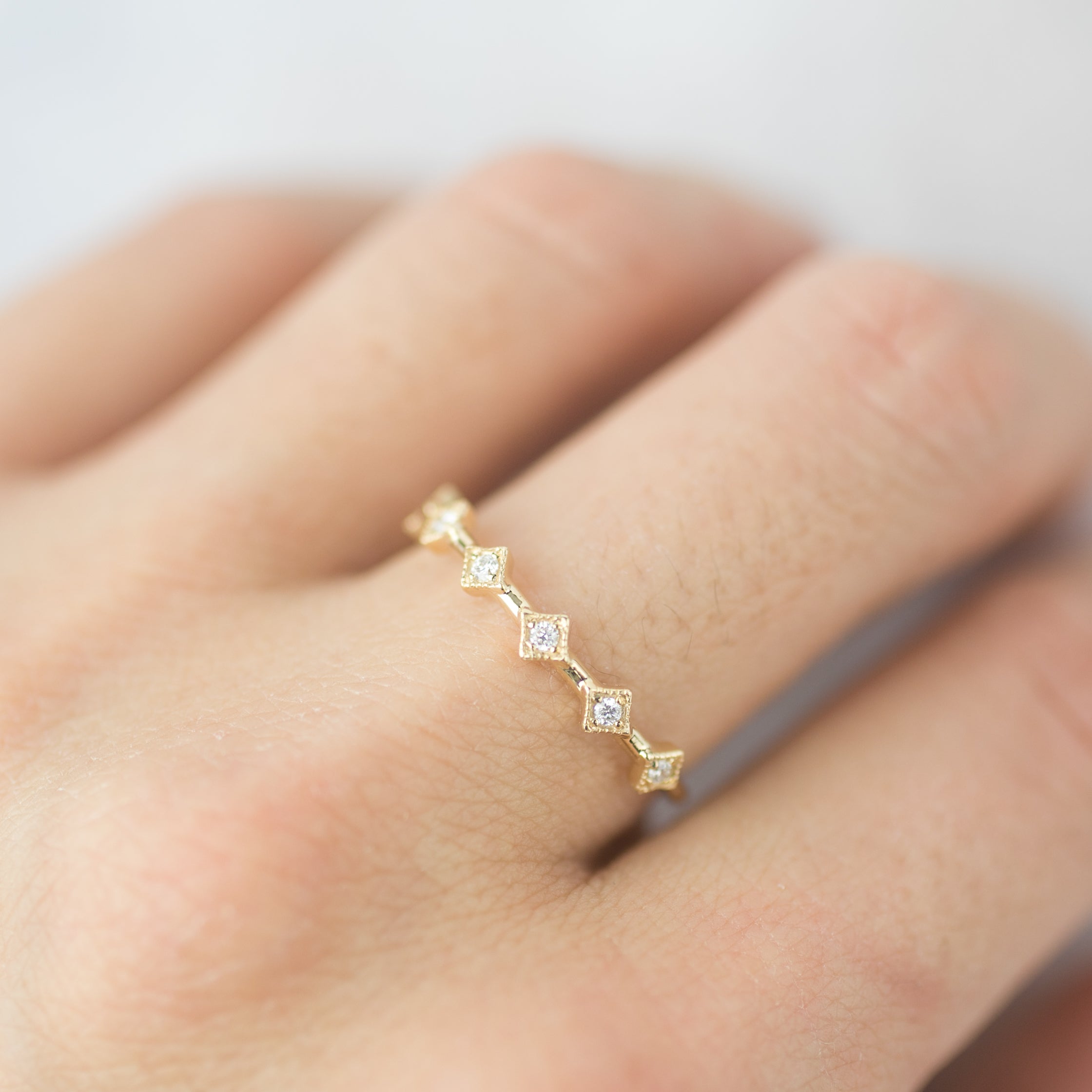 Close-up of a Six Star Ring with natural white diamonds set in solid gold on a finger, packaged in kraft box.