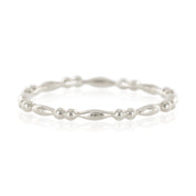 Close-up of a delicate beaded silver eternity ring with alternating small round and elongated beads on a white background