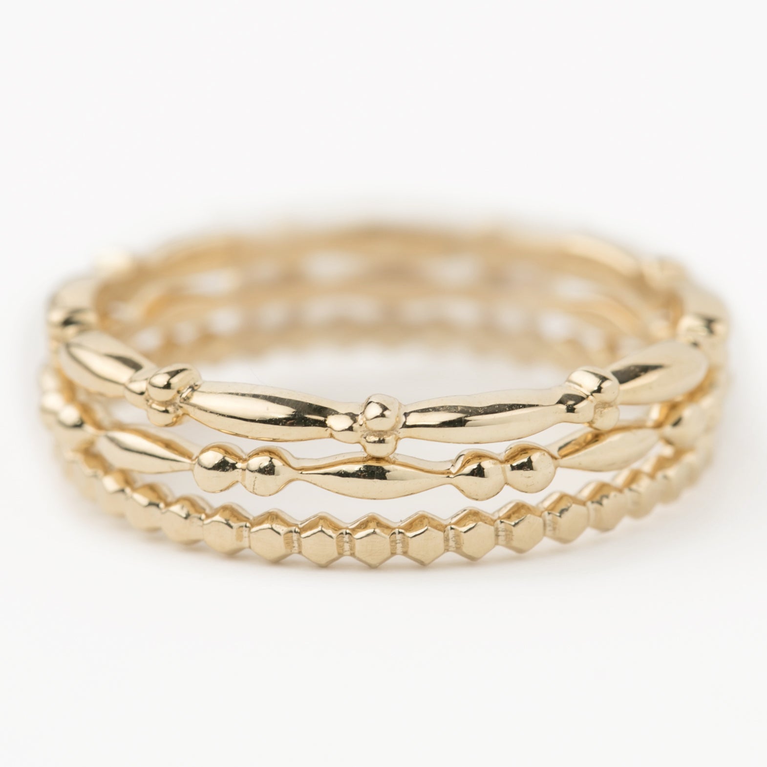Set of three 14k solid gold beaded stacking rings with unique textured bands in yellow gold.