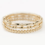 Set of three 14k solid gold beaded stacking rings with unique textured bands in yellow gold.