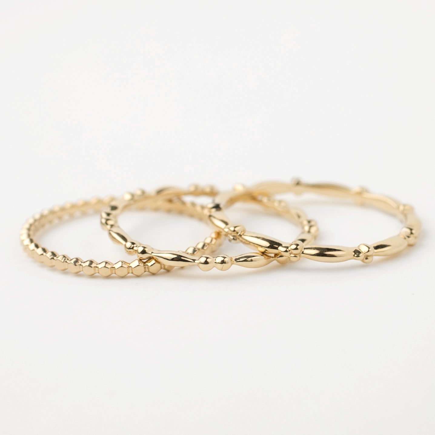 Set of 3 delicate 14k solid gold beaded stacking rings with unique textures, perfect for layering or solo wear.