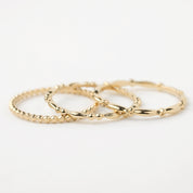 Set of 3 delicate 14k solid gold beaded stacking rings with unique textures, perfect for layering or solo wear.