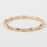 Close-up of a 14k solid yellow gold beaded stacking ring with a 1.5mm band, handmade with detailed texture.