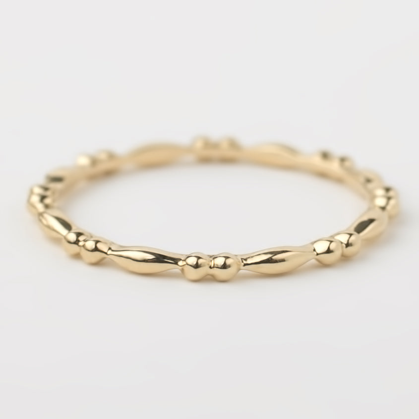 Close-up of a 14k solid yellow gold beaded stacking ring with a 1.5mm band, handmade with detailed texture.