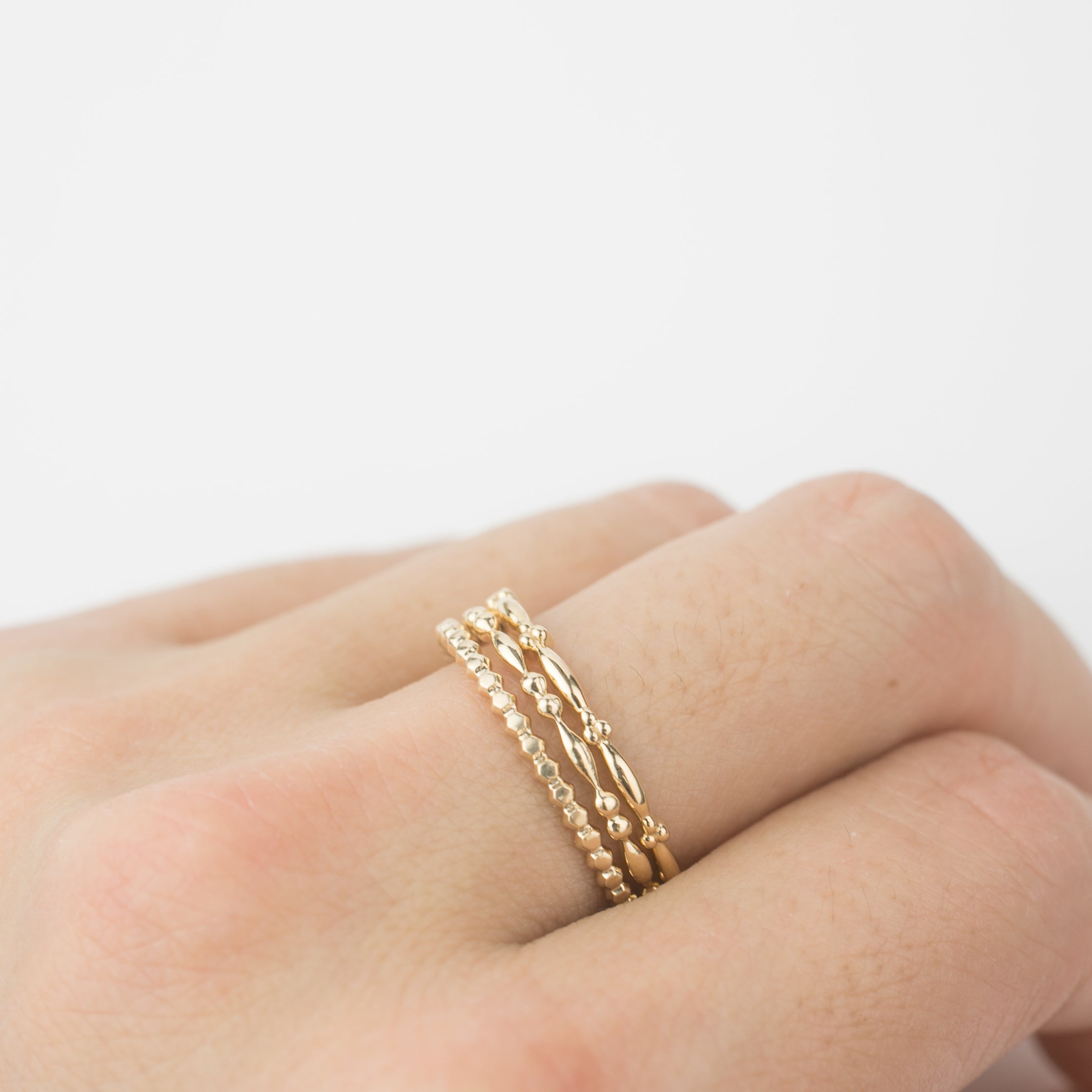 Set of 3 14k solid gold beaded stacking rings worn on finger, dainty and versatile design in yellow gold
