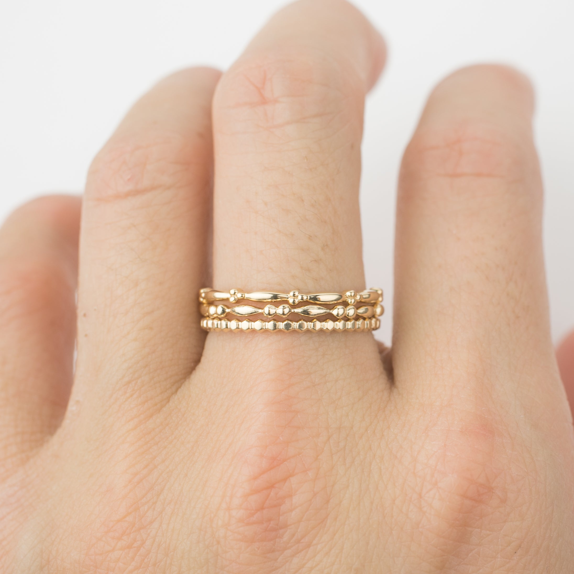 Set of 3 unique 14k solid gold beaded stacking rings worn on finger with dainty band details.