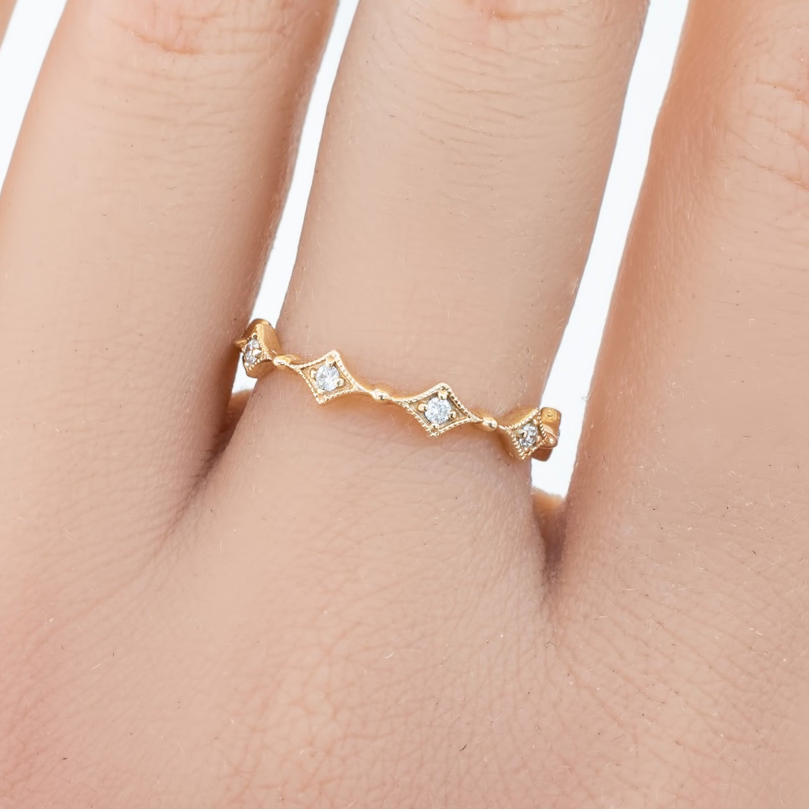 Gold star diamond eternity ring with small white diamonds worn on hand finger close-up view