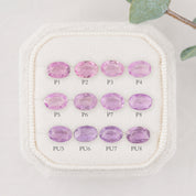 Nine oval-cut pink and purple gemstones arranged in a 3-by-3 grid on a white textured display pad, with labels P1 through PU8 beneath each stone.