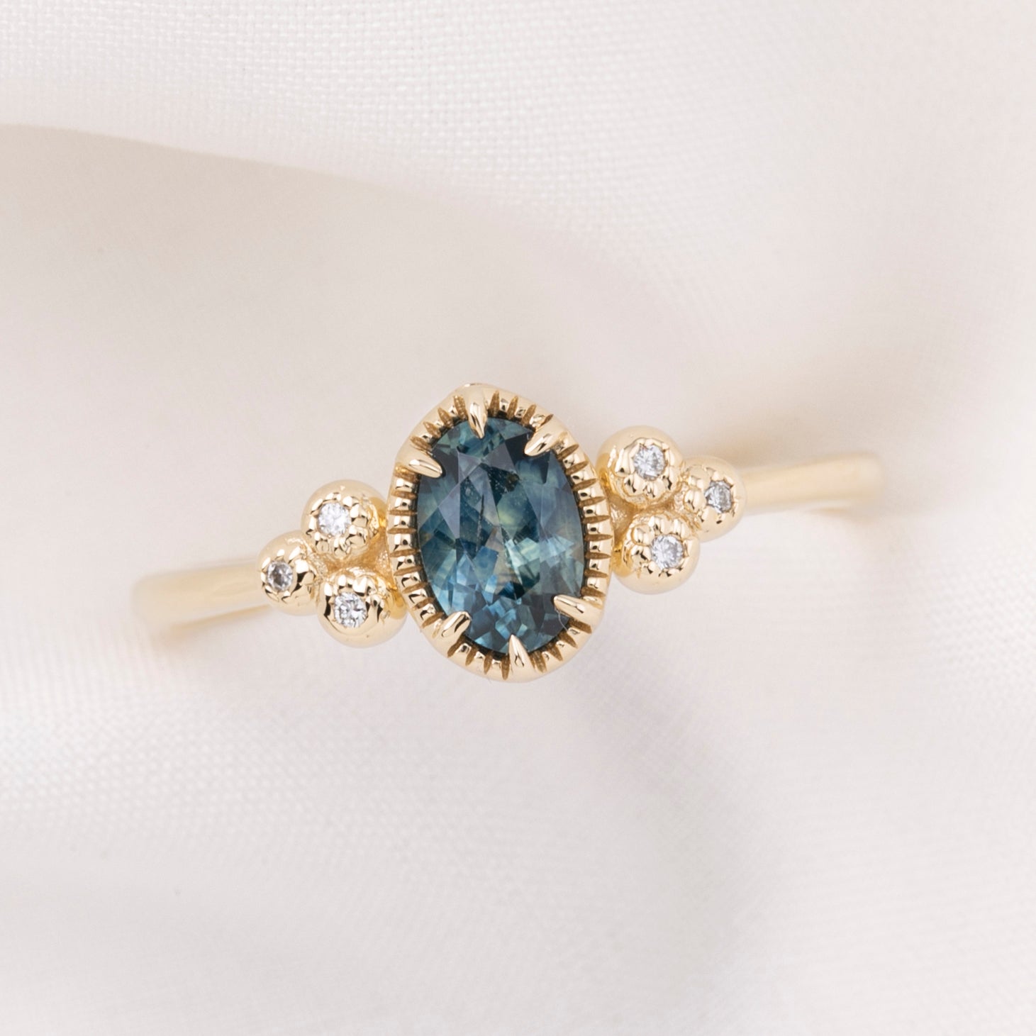 Celine Ring featuring a 0.60ct teal-blue Montana sapphire in a 14k yellow gold with six natural diamond accents