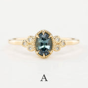 Gold ring with a central blue gemstone and diamond accents on a light gray background