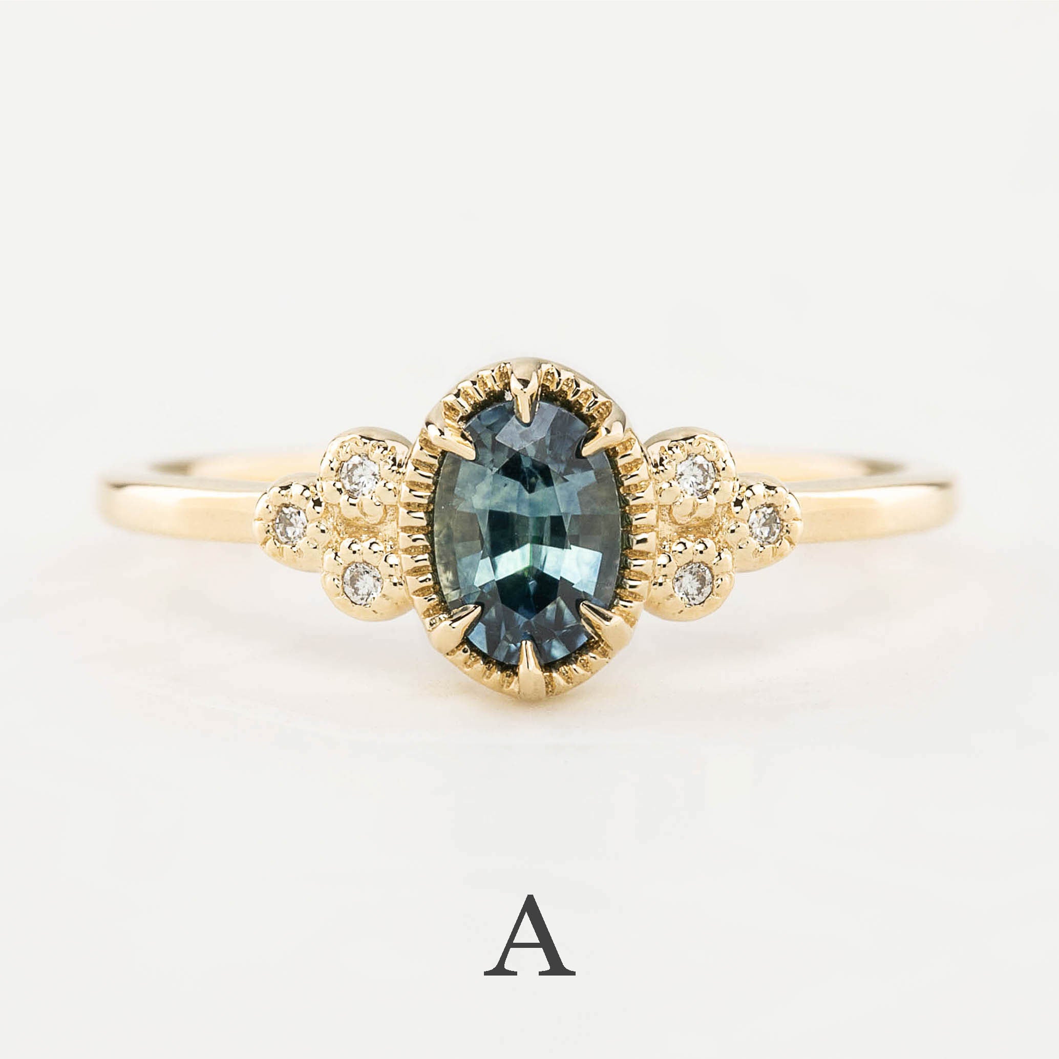Gold ring with a central blue gemstone and diamond accents on a light gray background