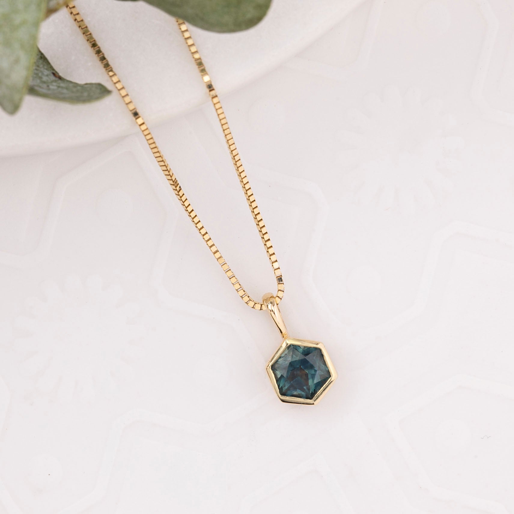 Gold necklace with a hexagonal pendant on a light background