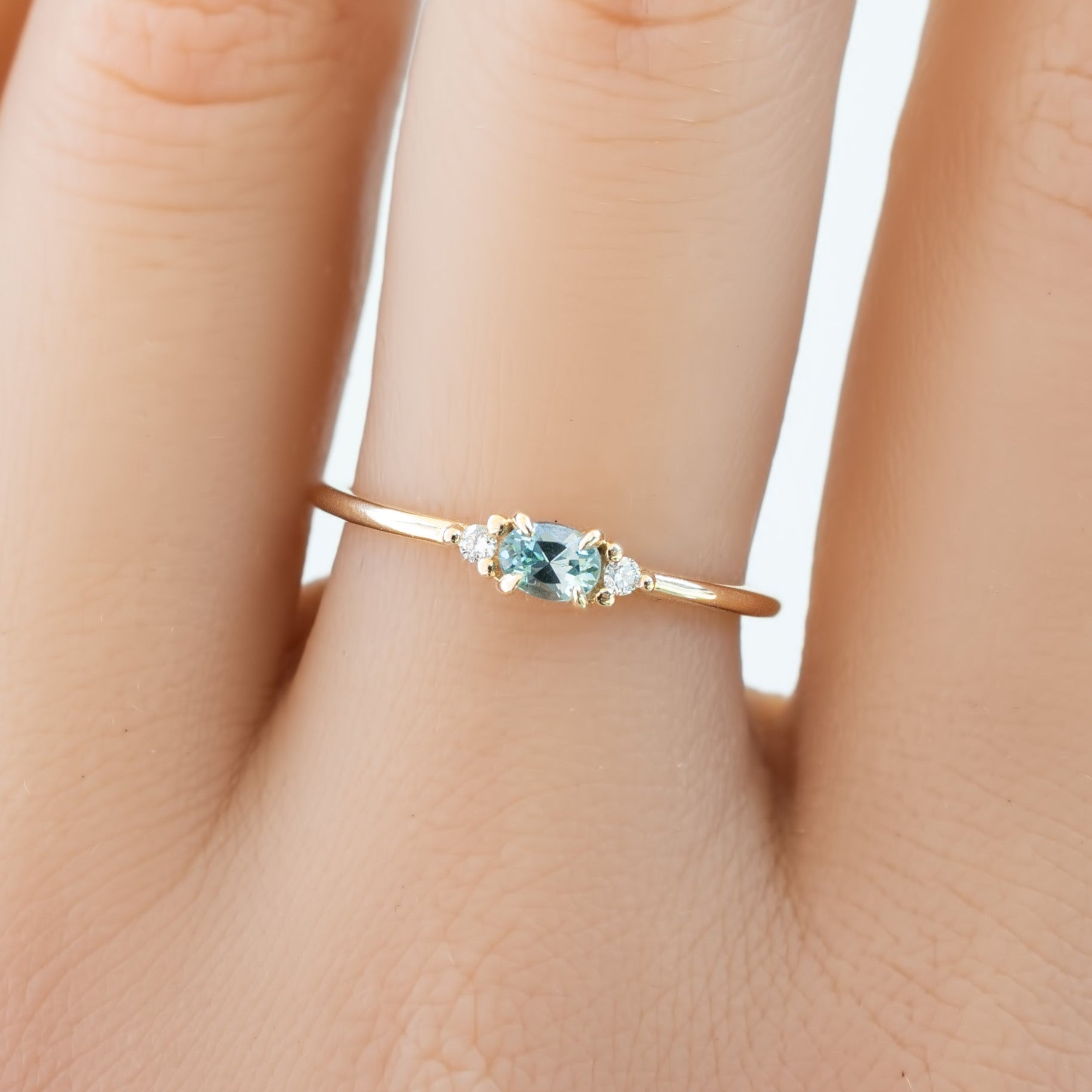 Emilie Ring featuring a 0.20ct East-West set oval Montana sapphire in 14k yellow gold on the hand.