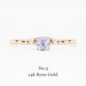 14k rose gold ring with a purple gemstone on a white background