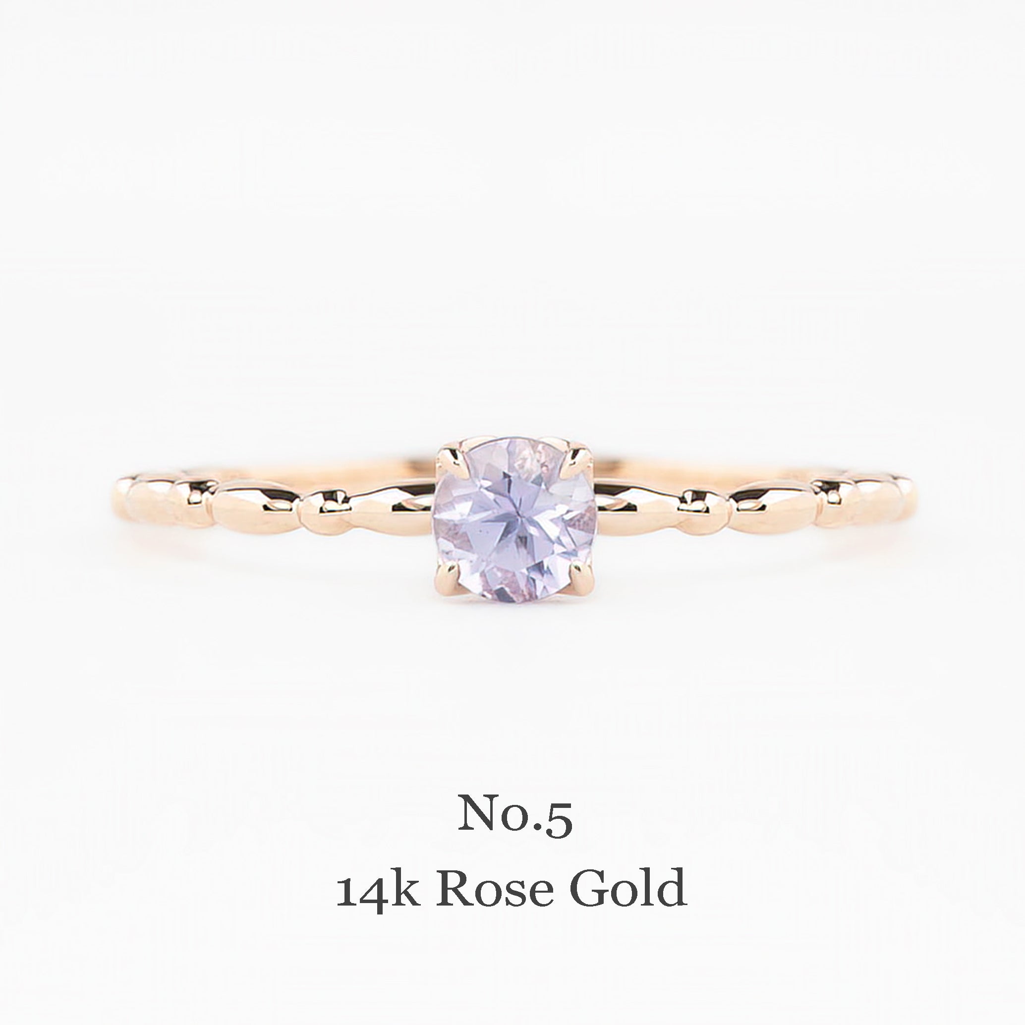 14k rose gold ring with a purple gemstone on a white background
