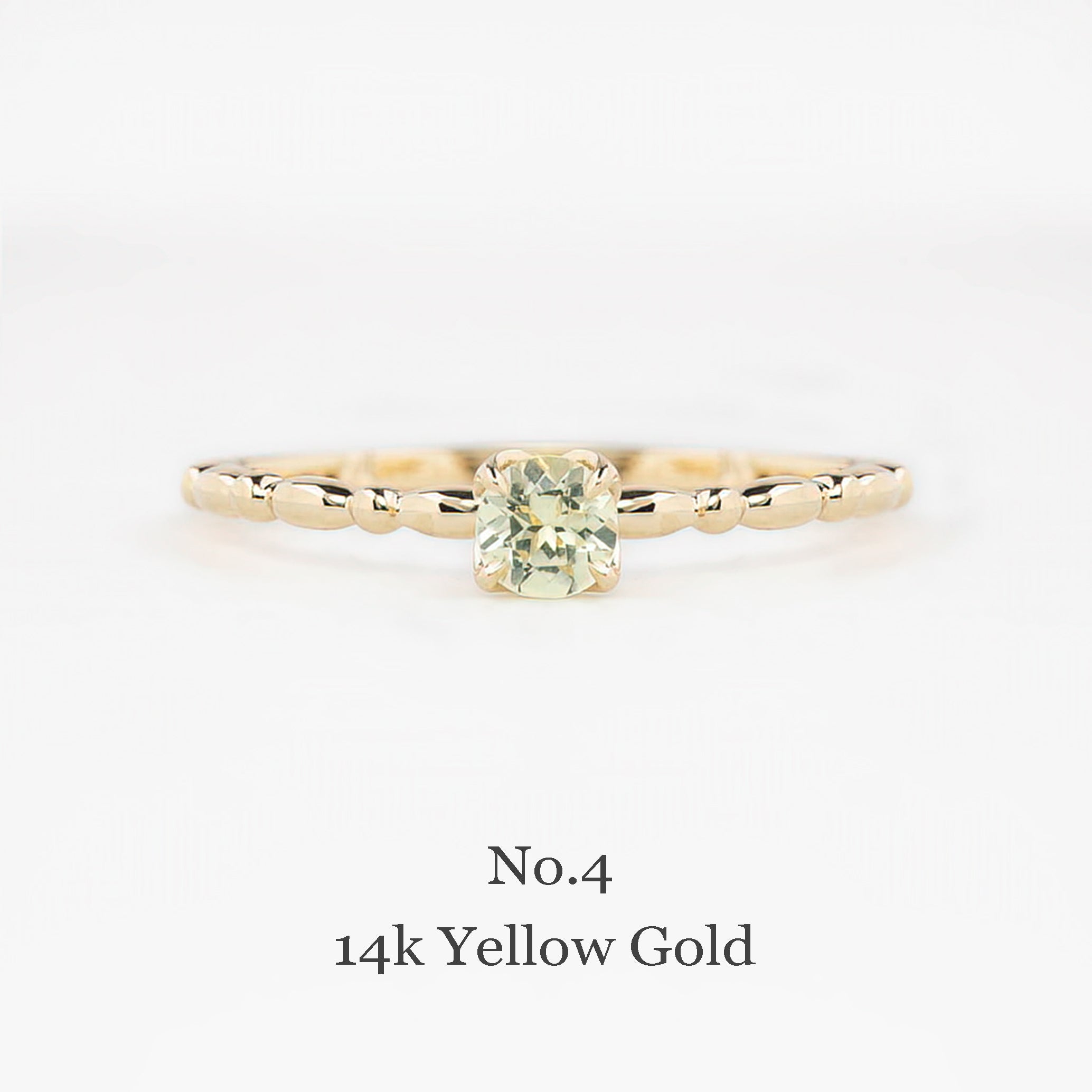 Gold ring with a green gemstone on a white background