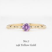 Gold ring with a purple gemstone on a white background