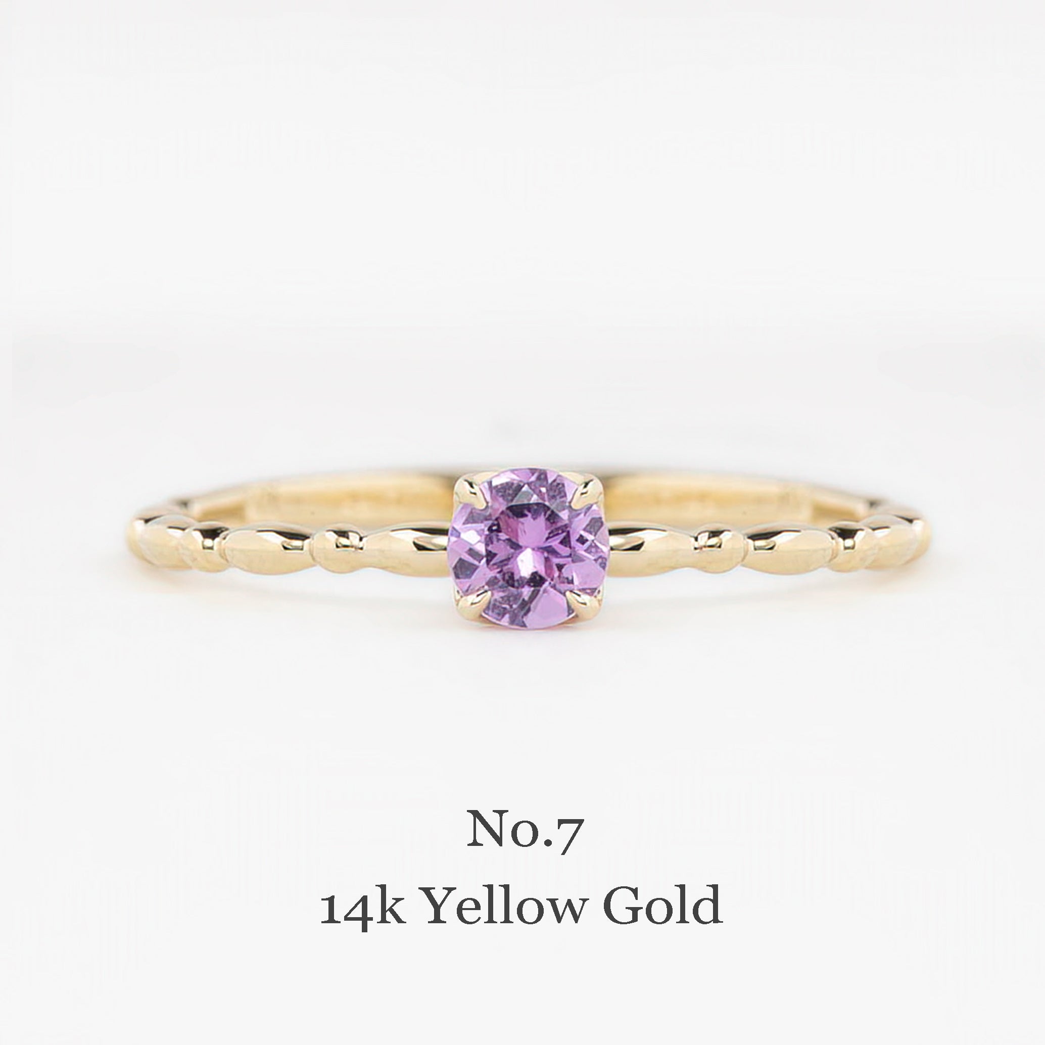 Gold ring with a purple gemstone on a white background