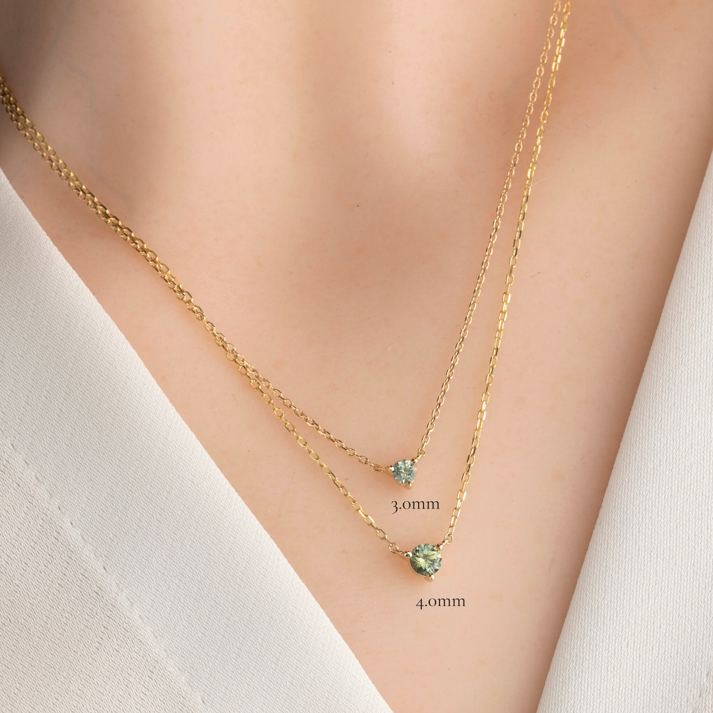 Comparison of 3.0mm Light Blue Green Sapphire Pendant Necklace next to 4.0mm Green Sapphire Pendant Necklace in 14k yellow gold on a model