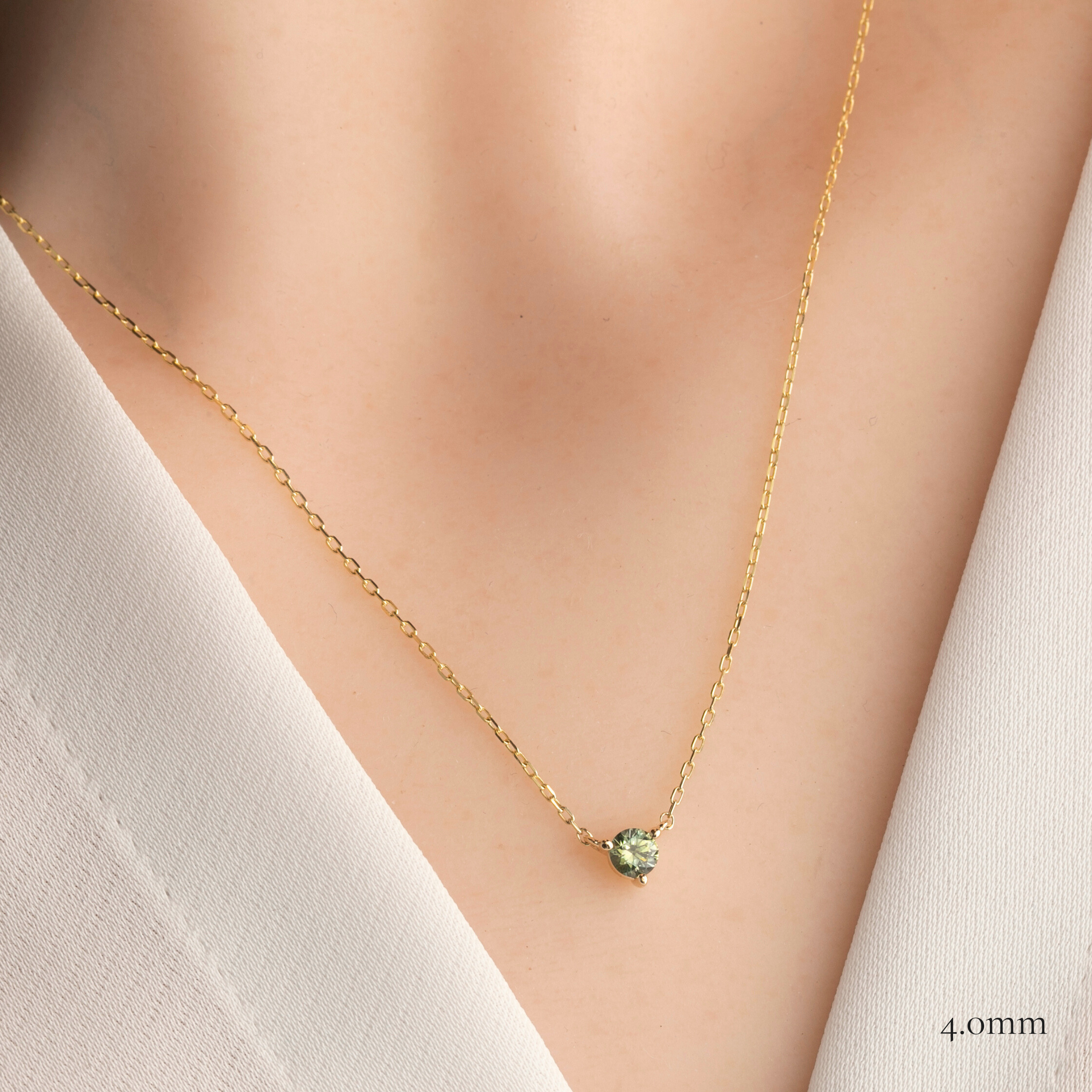 Gold necklace with a green round 4.0mm sapphire 3 prongs pendant on a model