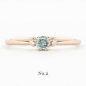 Rose gold ring with a green gemstone on a white background