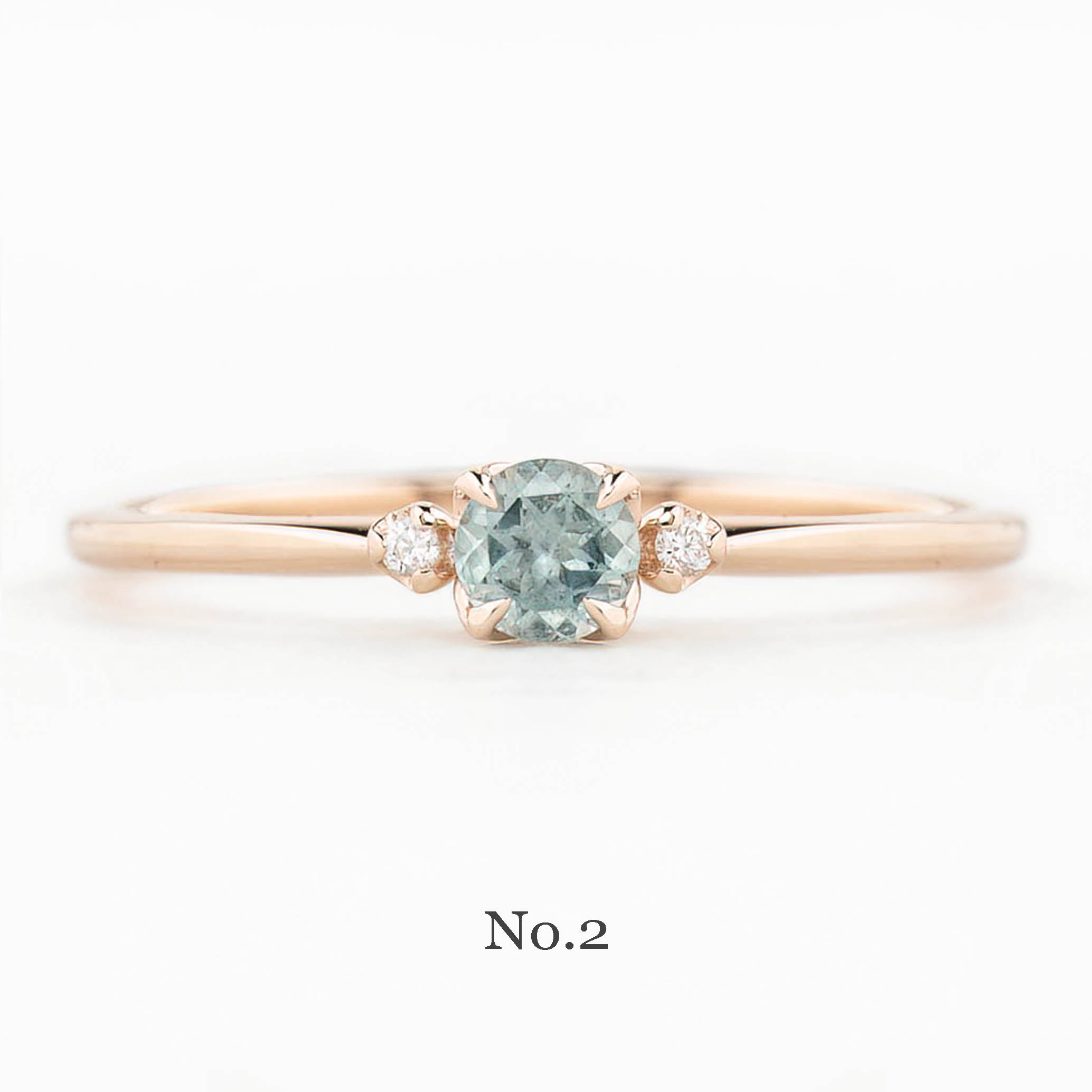 Rose gold ring with a green gemstone on a white background