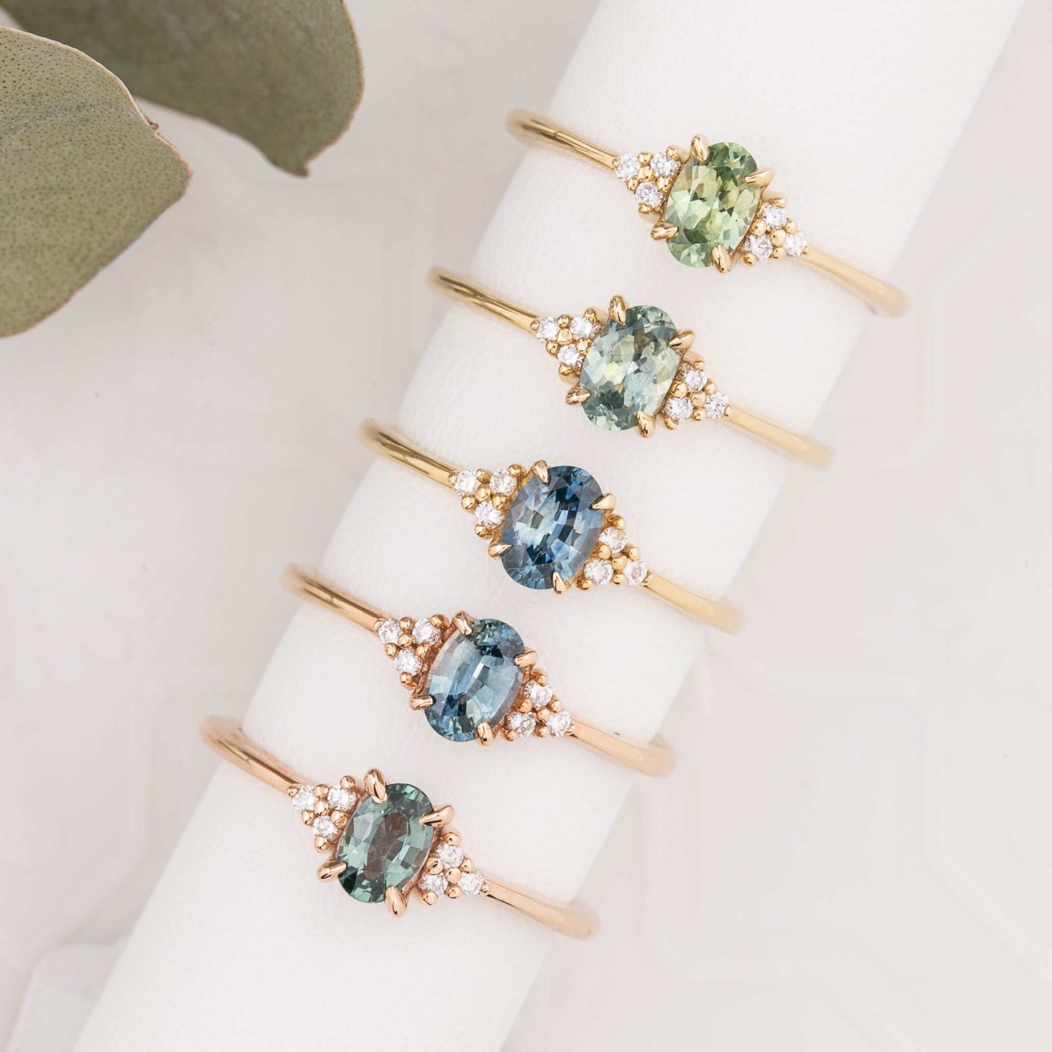 Set of gold rings with green gemstones on a white surface
