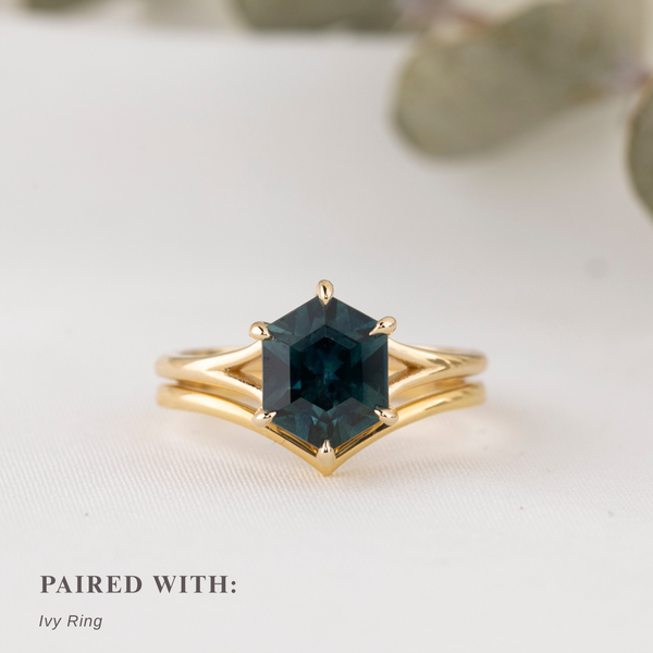 Gold ring with a green gemstone on a light background stacked with plain gold curved ring