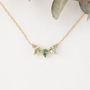 Gold necklace with green gemstones on a white background