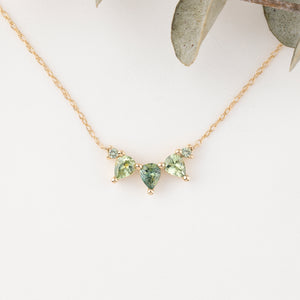 Gold necklace with green gemstones on a white background
