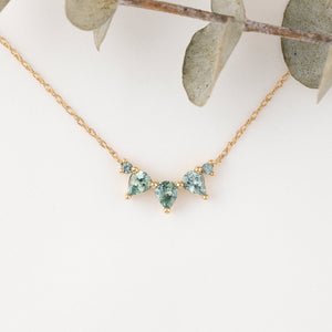 Gold necklace with green gemstones on a white background