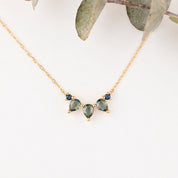 Gold necklace with green gemstones on a white background