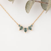 Gold necklace with green gemstones on a white background