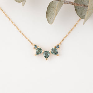 Gold necklace with green gemstones on a white background