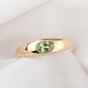 Gold ring with a green gemstone on a white background