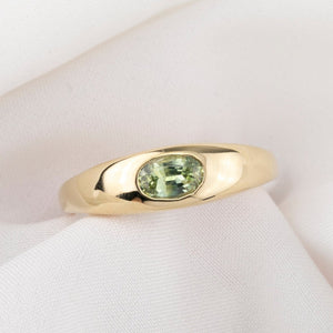 Gold ring with a green gemstone on a white background