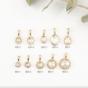 Set of gold pendants with clear stones on a white background