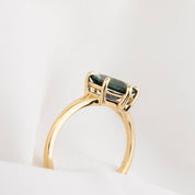 side view of Gold ring with a green gemstone on a white background
