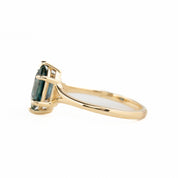 Gold ring with a green gemstone on a white background - side view