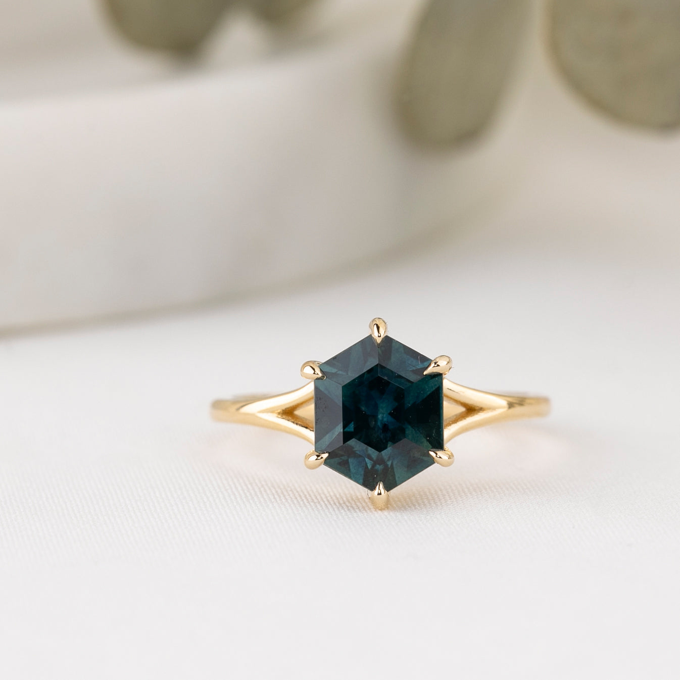 Gold ring with a green gemstone on a light background