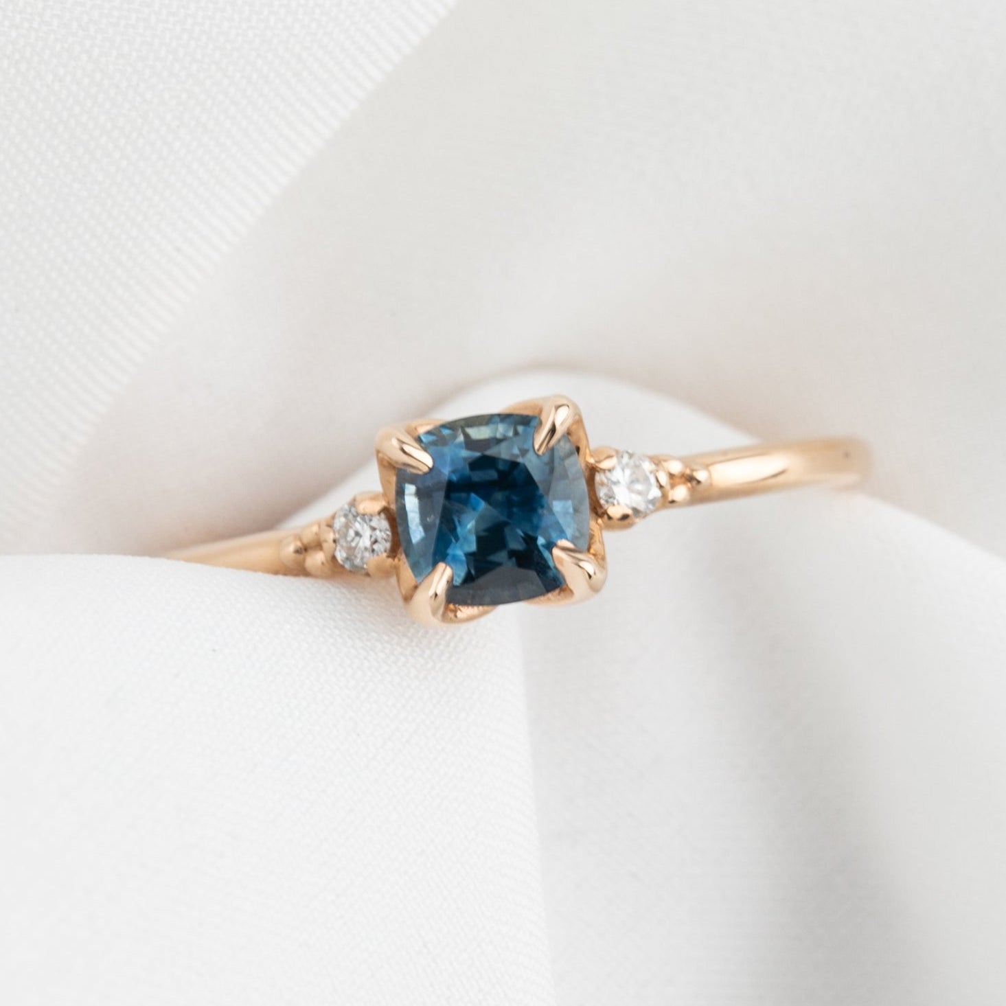 Rose gold ring featuring a 0.76ct cushion cut Montana sapphire with natural diamond accents in four prong setting