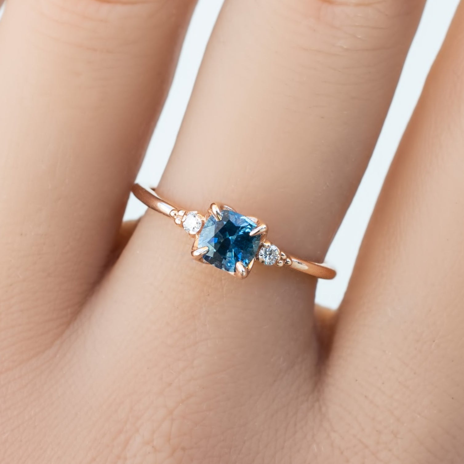 0.76ct cushion Montana sapphire ring with natural diamonds in 14k recycled rose gold on finger size 7